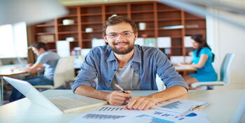 Handsome businessman in casual looking at camera in office on background of his partners