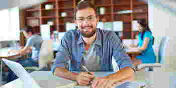 Handsome businessman in casual looking at camera in office on background of his partners