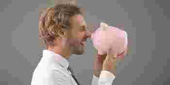 Handsome man with piggy bank on grey background